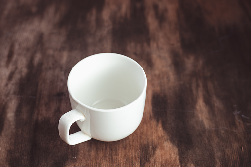 White empty cup of coffee on blur background. empty coffee cup or tea cup on the dark wooden table. Empty white Cup on a wooden background, top view . Crockery for coffee and tea