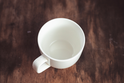White empty cup of coffee on blur background. empty coffee cup or tea cup on the dark wooden table. Empty white Cup on a wooden background, top view . Crockery for coffee and tea