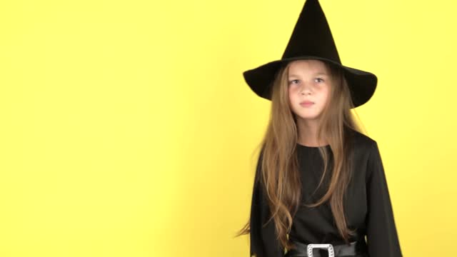 A little girl on a yellow background shows emotions, the concept of the holiday Halloween