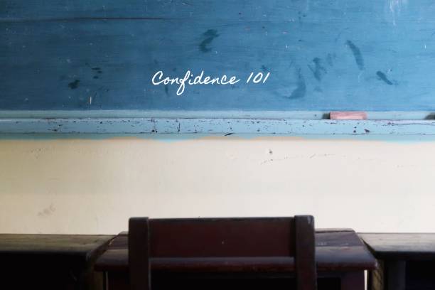 istock Green vintage school  chalkboard background , with handwritten chalk text CONFIDENCE 101 - with student old wood desk and chair as foreground. 1656392524