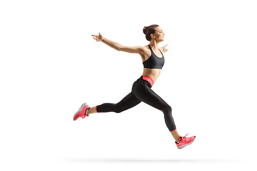 Full length profile shot of a fit young woman running and spreading arms isolated on white background