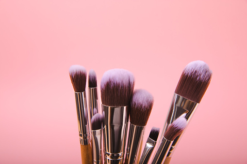 Cosmetic product for makeup. Makeup brushes on a pink background. Creative fashion concept. Collection of cosmetic makeup brushes, top view, banner.Flat lay.