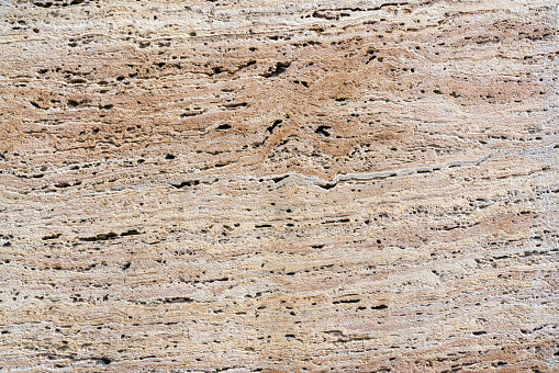 Close-up of porous surface of travertine stone slab with beautiful beige pattern