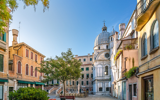 Marble church of Santa Maria dei Miracoli among old houses around empty small square early in morning