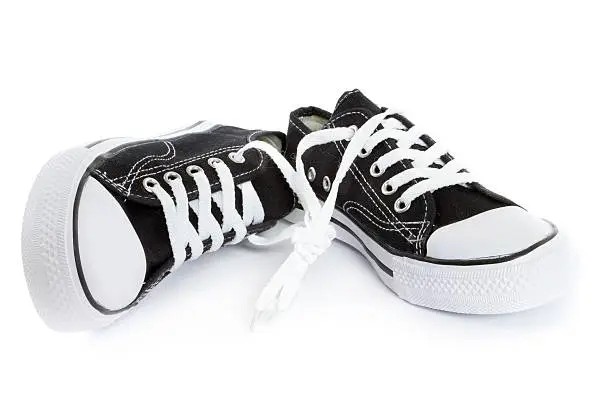 tied, brand new black and white tennis shoes on white background.