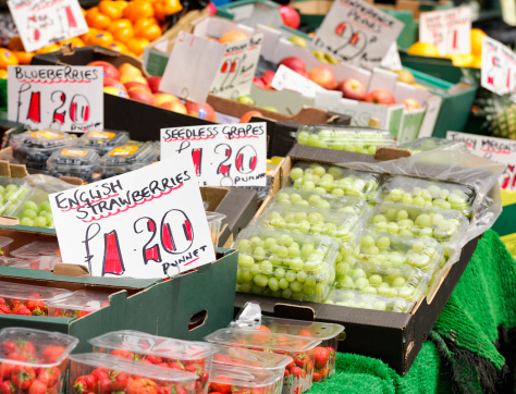 Punnets of fresh strawberries, grapes and blueberries on display at an English market during summer.