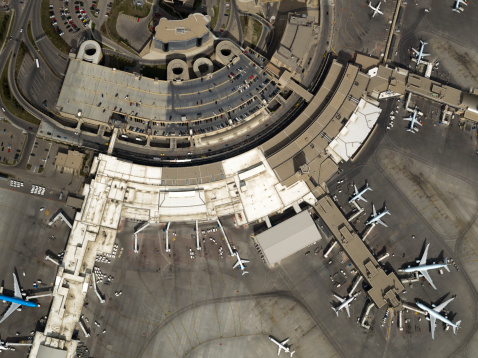Aerial photo of a busy international airport with many planes parked at the gate.