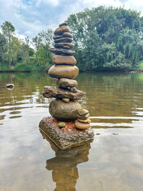 istock Rock stack Cairn in the brown river.  Water surrounding the stack with green trees and cloudy skies in the distance.  Gold Coast Queensland Australia 1656509958