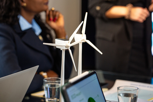 Company meeting for a new project on renewable energy. Meeting room with wind turbines in the foreground and a blurred background