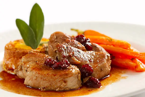 Medallions of pork loin pan seared and served with a port wine and dried cherry pan sauce, arranged on the plate with a squash flan and oven roasted carrots.