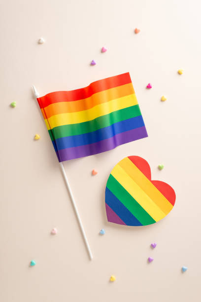 istock Flat lay vertical composition with LGBT- themed accessories including rainbow flag, big heart and small decorative hearts on beige backdrop 1656579530