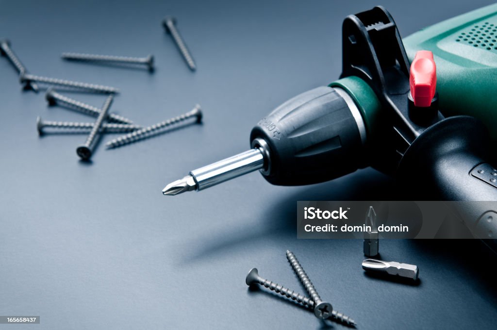 Electric drill with screws and screwdrivers on dark background Composition of electric drill with screws and screwdrivers on dark background. Power Tool Stock Photo