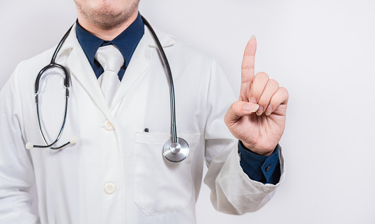 Unrecognizable doctor pointing up. Hand of doctor pointing up. Doctor finger pointing up with text space