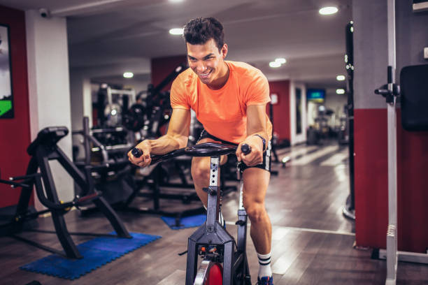 One man, fit man exercising on exercise bike in gym alone.