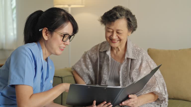 A female caregiver looks after the medication of an elderly woman at home.