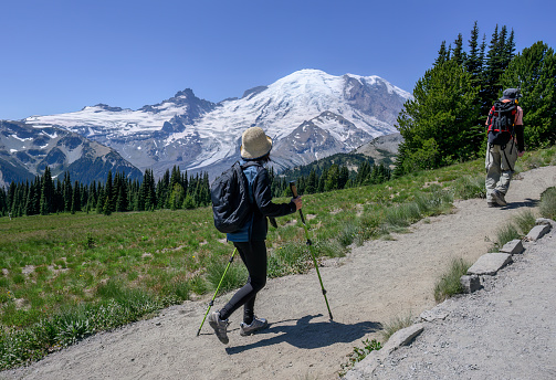 Two people hiking Sunrise Trail at Mount Rainier National Park in summer. Washington State.