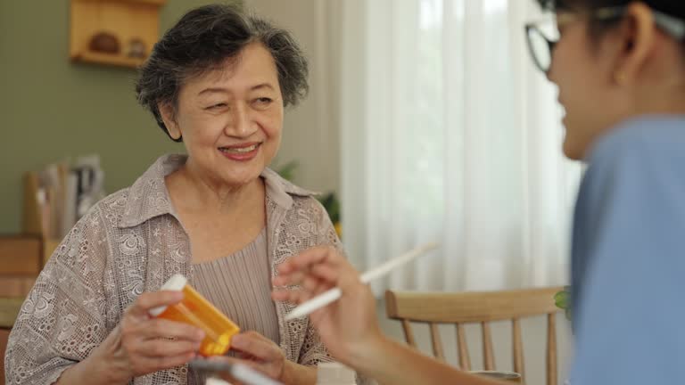 A female caregiver looks after the medication of an elderly woman at home.