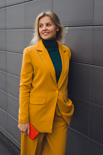 Young smiling blonde woman wearing fashion yellow jacket outdoors portrait