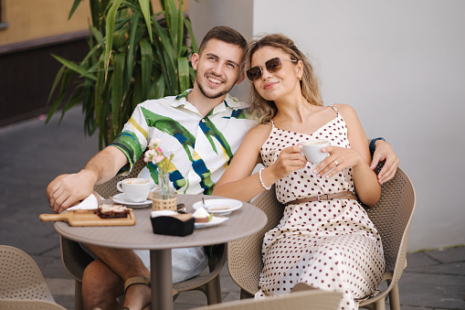 Portrait of man and woman sitting together in cafe on terrace and have good time. High quality photo