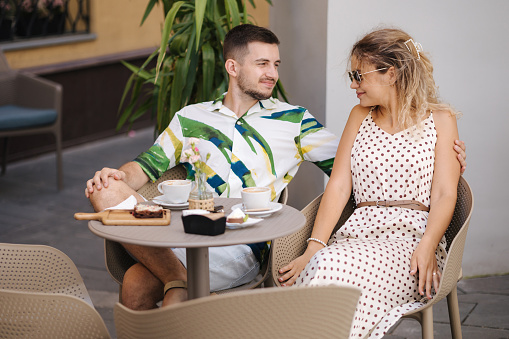 Happy couple of man and woman sitting in cafe and drink coffee. High quality photo