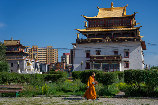 Ulaanbaatar, Mongolia - July 16, 2023: Two monks walk past a building near the Gandantegchinlen Monastery.