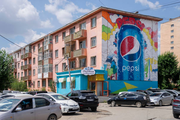 Ulaanbaatar, Mongolia - July 21, 2023: Vehicles are seen in front of a residential building with a large Pepsi mural.