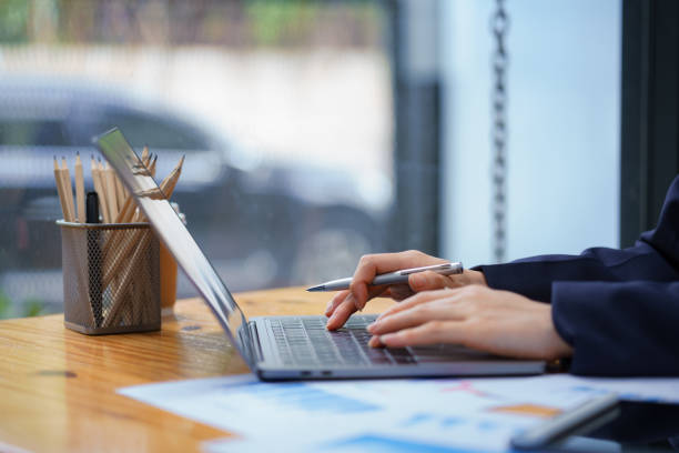 istock Close-up hand Asian woman holding a pen using a laptop. 1656689671