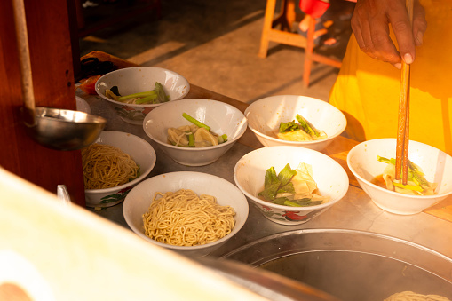 a chicken noodle seller is preparing chicken noodles for customers. Mie ayam is a popular Indonesian street food.