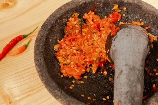 Sambal or traditional chili sauce from Indonesia, freshly made using stone mortar and pestle