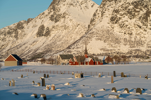 With snow covered graveyard and red wooden church in background on Lofoten islands , Nordland, Norway