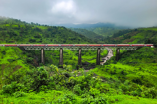 Igatpuri Indian Railway Train crossing bring through the mountain range of western ghats. It is monsoon season and raining heavily ND Valley is green.