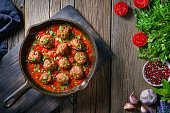 Meat balls with tomato sauce homemade in rustic cast iron pan over wood