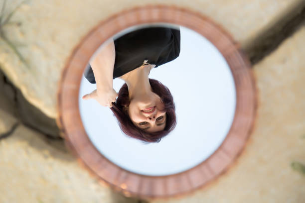istock A woman looks into a mirror lying on the ground, a mirror found by chance 1656815733