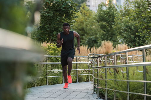 Handsome African man in sportswear looking concentrated while running outdoors
