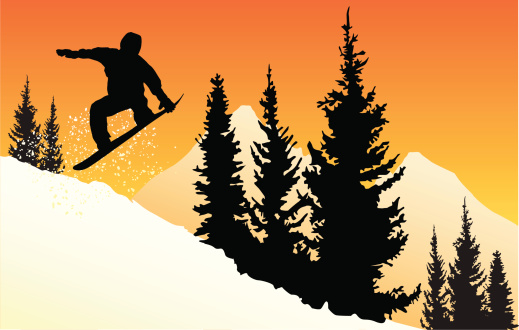 Silhouette of a snowboarder against an orange sunset in the mountains.