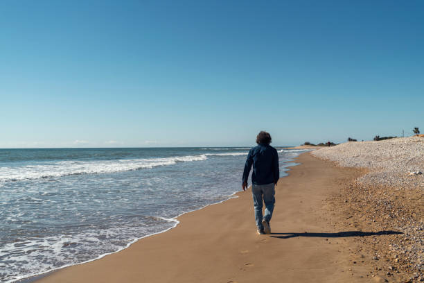 istock A man walking along the deserted beach 1656882698