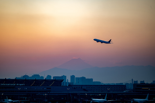 An airplane takes off from Airport in the evening. You can see Mt.Fuji in the background.