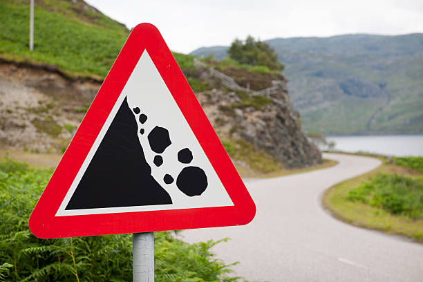 Falling Rocks Warning Road Sign There may be trouble ahead - a rural road sign warning of a danger of falling rocks around the corner on a road in Scotland. avalanche stock pictures, royalty-free photos & images