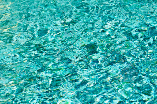 Blue-green  rippled water surface of a fountain pool. Background. Horizontal orientation.