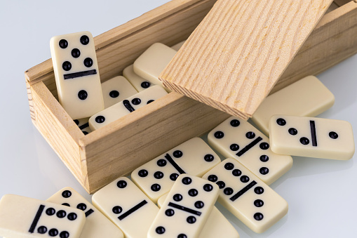 white domino tiles stacked in a wooden box , photographed on a white background close-up