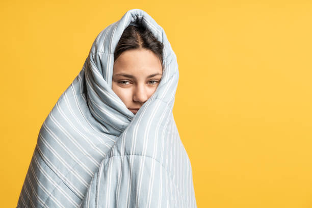 istock Sleepy girl wrapped in blanket smiling. Copy space. Isolated yellow studio background. 1657054676