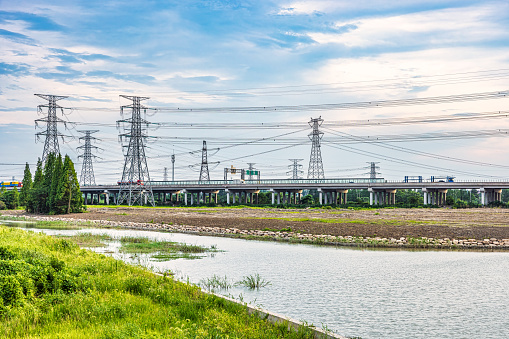 High voltage power tower and highway with river scenery, China