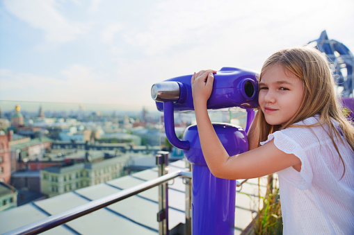 a teenage girl looks into the Binoscope from the observation deck at a height. A popular entertainment for tourists.