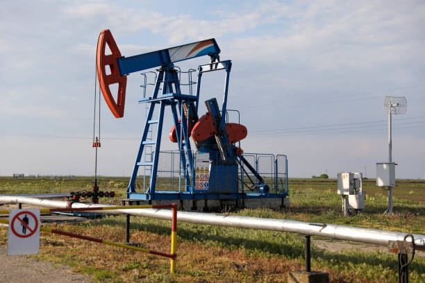 oil Operating oil and gas well profiled on bright sky with clouds in active European oilfield natural gas extraction stock pictures, royalty-free photos & images