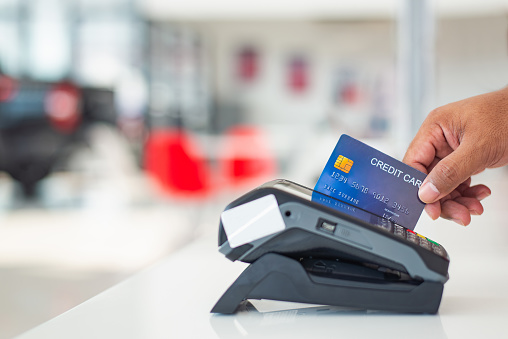 Credit card payment, purchasing and selling goods and services while holding a fake credit card in front of a credit card reader.