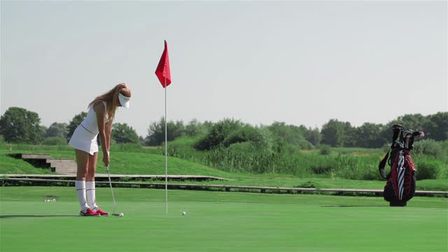 Woman prepares for the putting at the golf