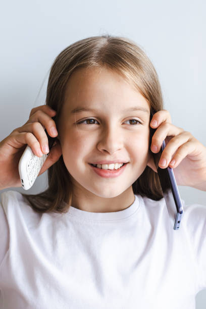 istock Cheerful girl talking on white push-button phone and smartphone vertical view 1657139053