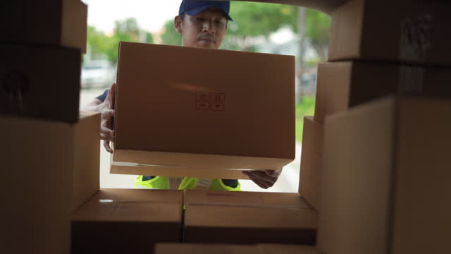 Delivery man take a package box in to transport van and checking inventory to prepare delivery to customer.