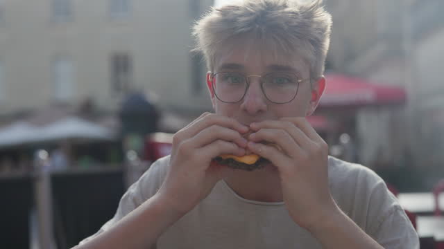 Hungry teenage boy eating a burger for lunch
