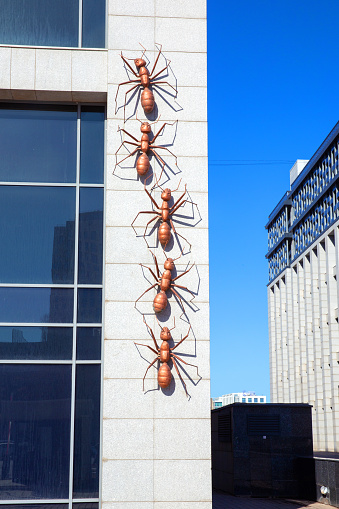 Astana, Kazakhstan - April 08, 2023: Metal ants crawl up wall. Unusual sculptures on the streets of the city